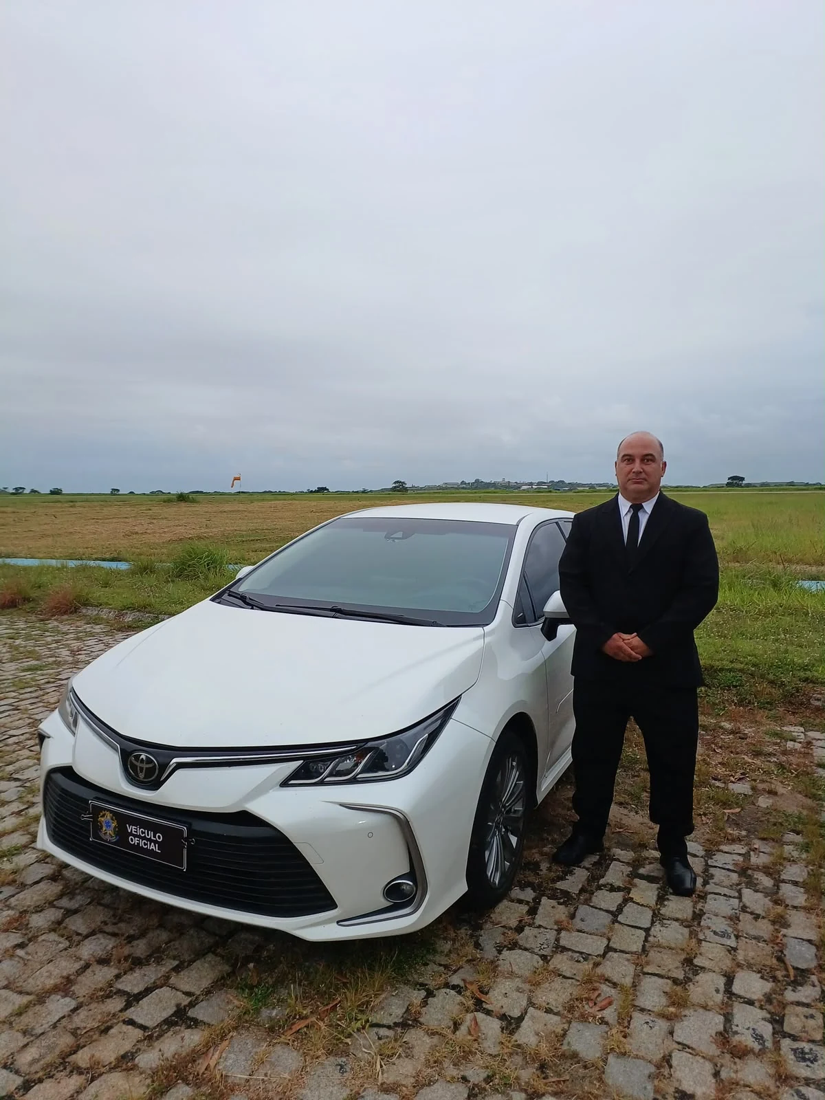 Motorista ao lado de veículo oficial branco