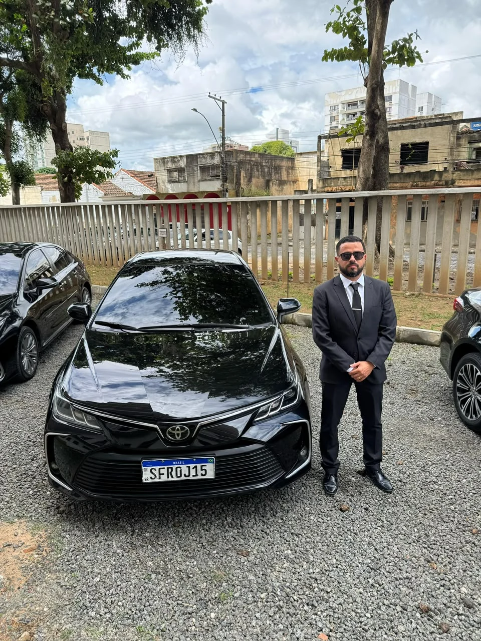 Profissional da Ernandes Transportes ao lado de carro executivo